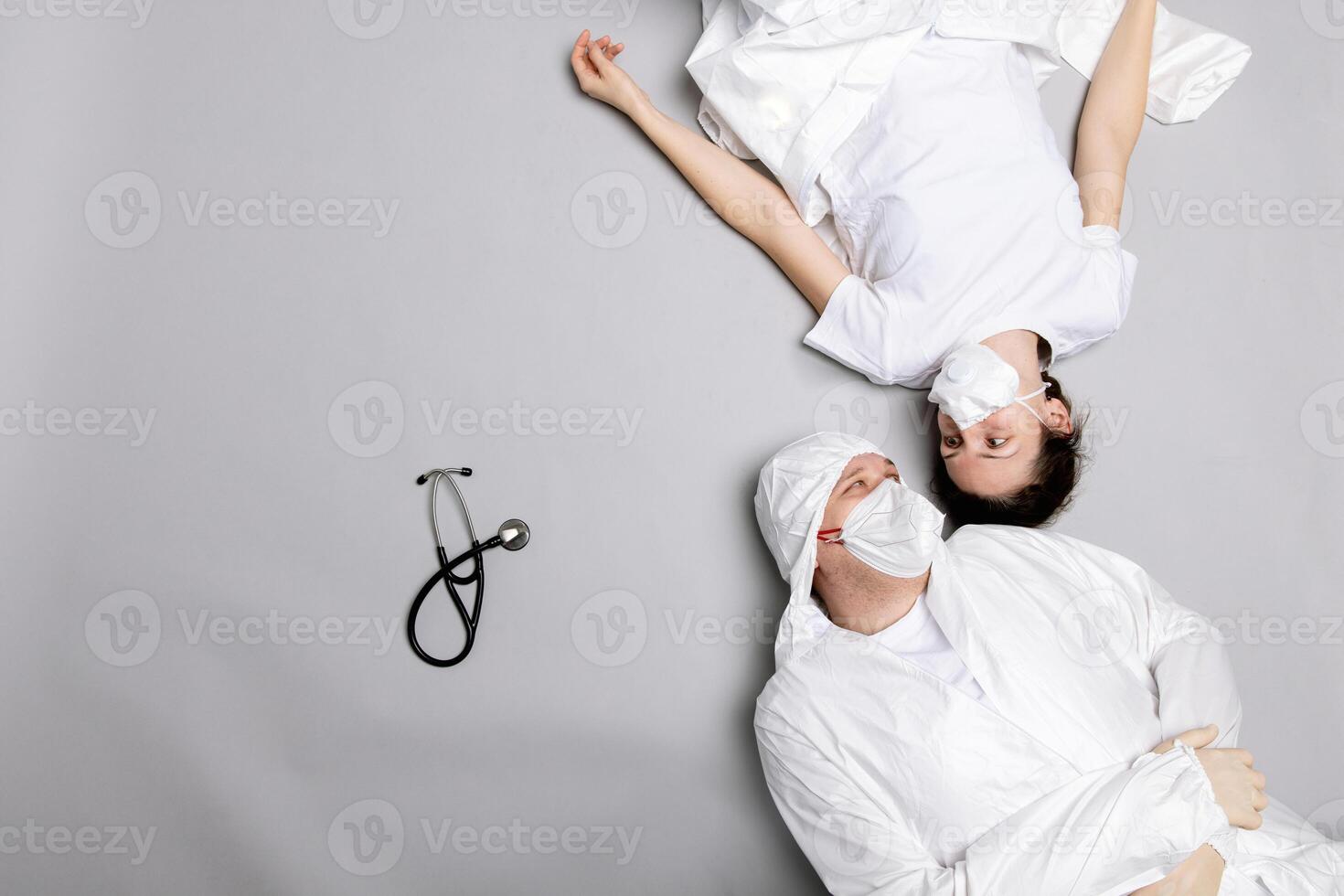 Two tired doctor male and female in a protective suit on the floor, exhausted photo