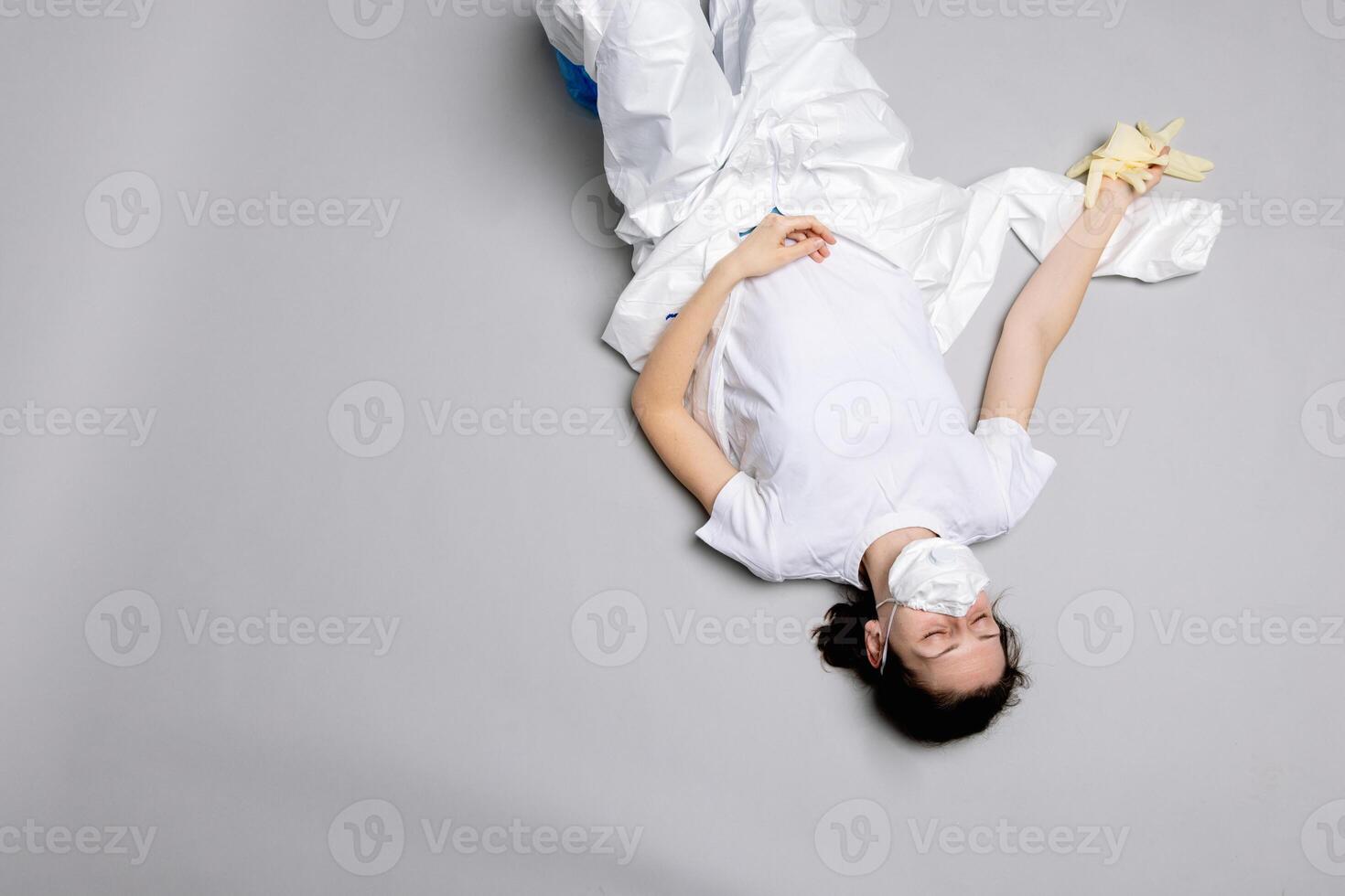 tired doctor female in a protective suit on the floor, exhausted photo