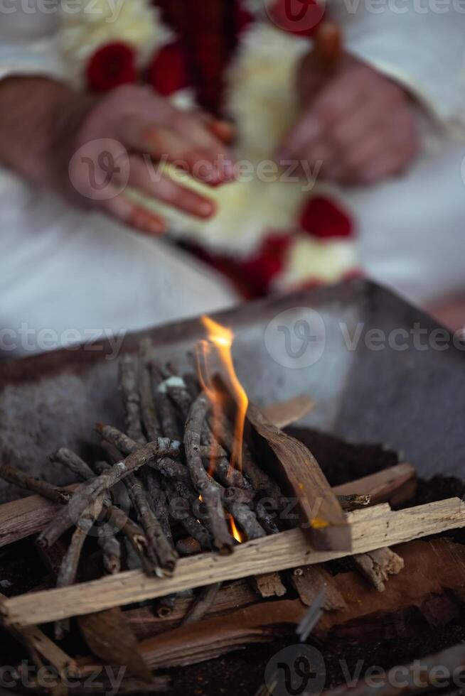 During an Indian wedding, a priest performs a ritual with fire and wood photo