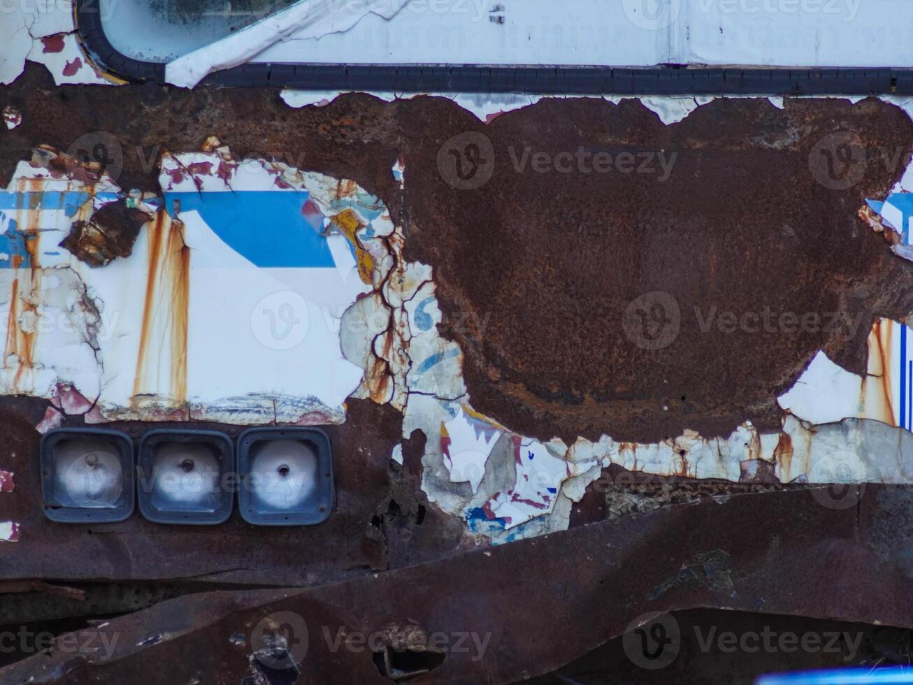 Rust on the front hood of an old car, close-up. An old abandoned rusty white car with damaged paint on the bumper and hood. photo