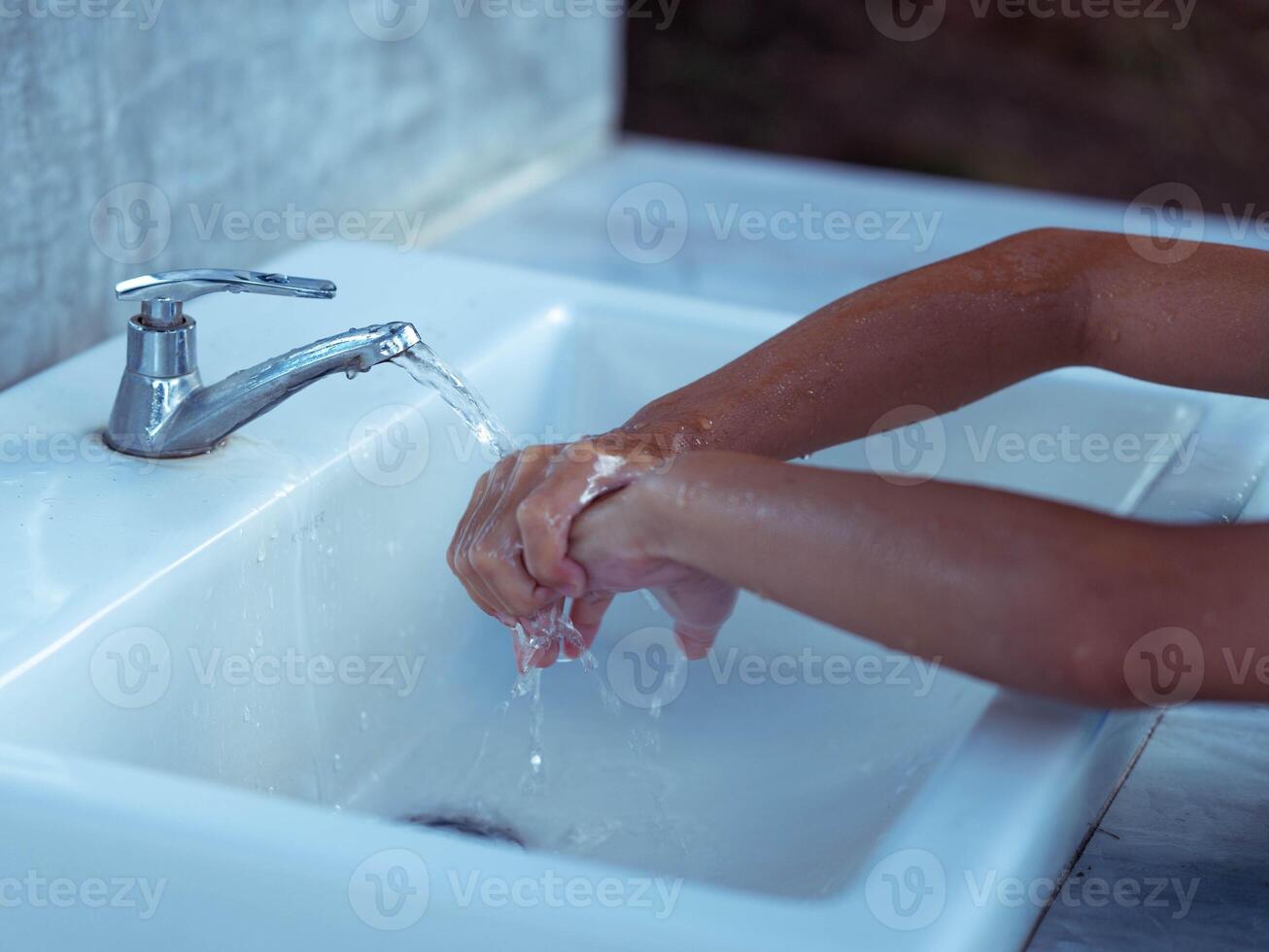 Close-up of hands being cleaned at a public faucet. photo