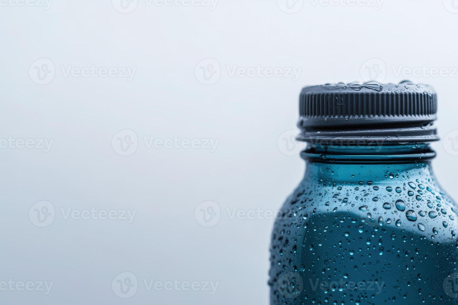 Close-up of a water bottle reflecting droplets against a gray background at morning light photo