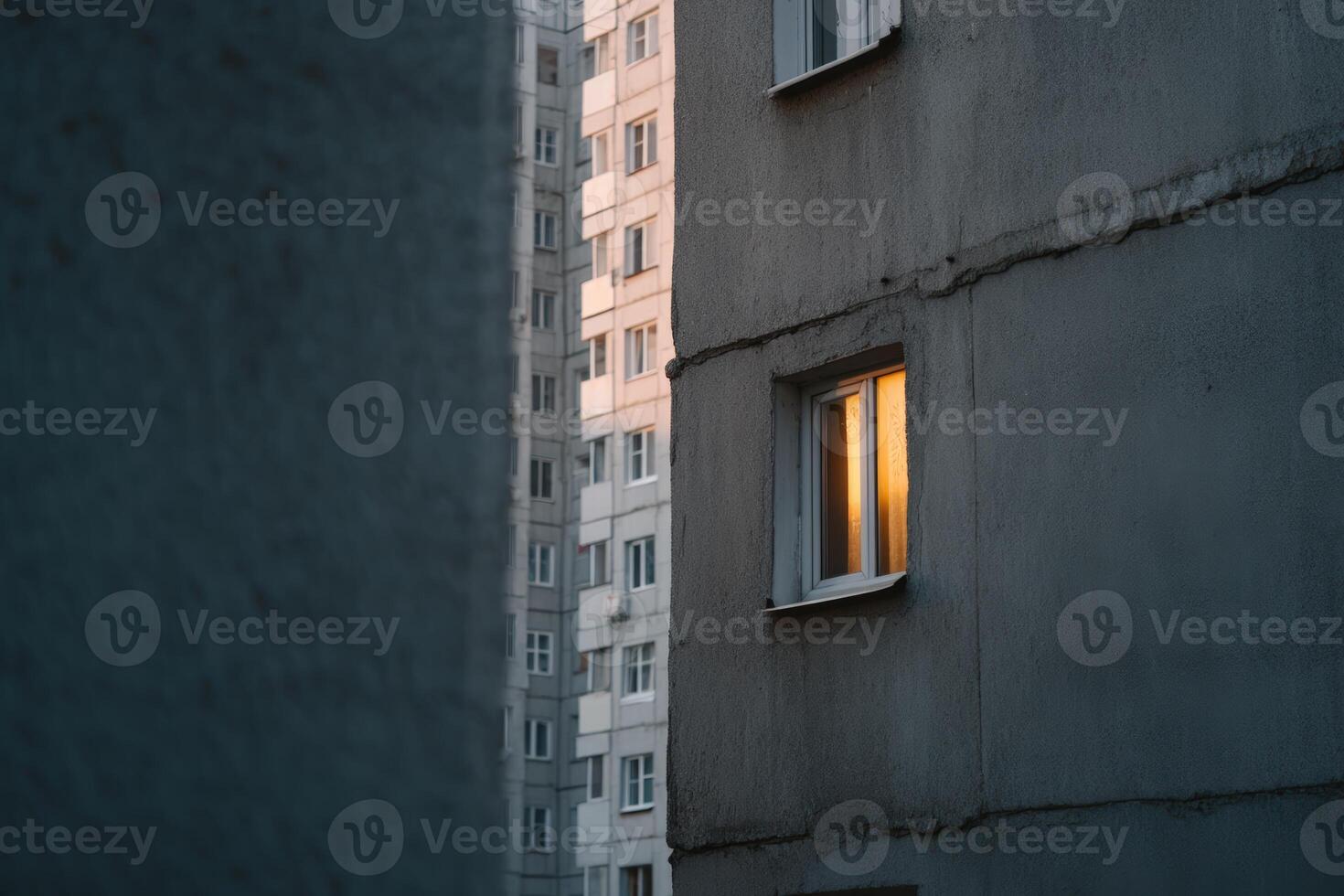 Evening light spills from a window in an urban apartment building photo