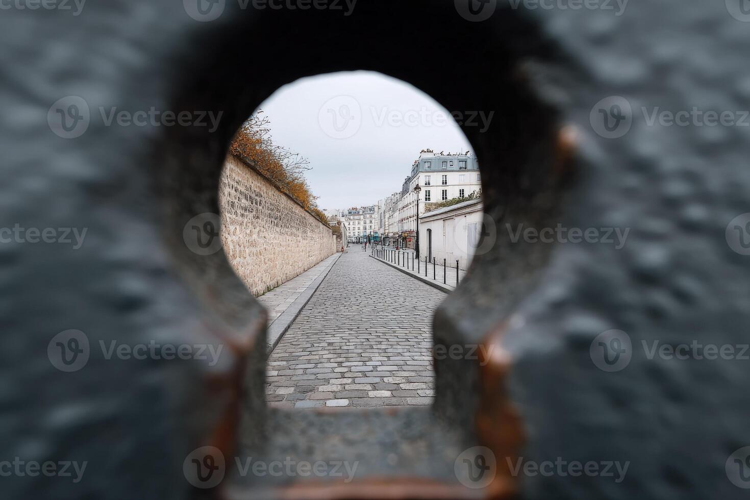 View through a keyhole of a cobblestone street in Paris on an overcast day photo