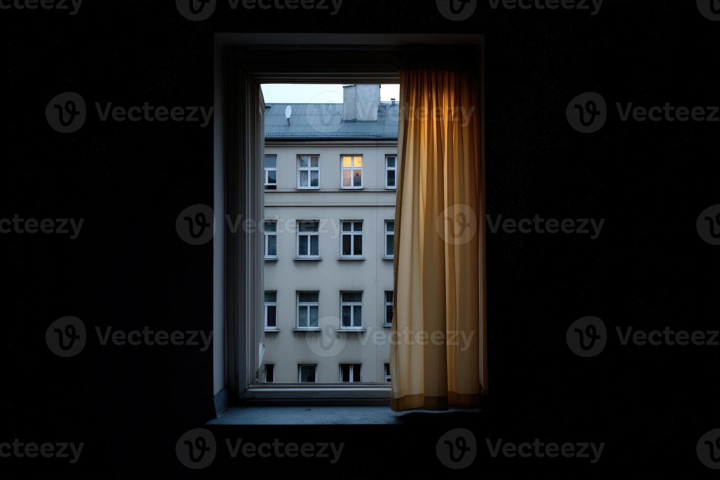 Late evening view through a window with a lit apartment in the distance photo
