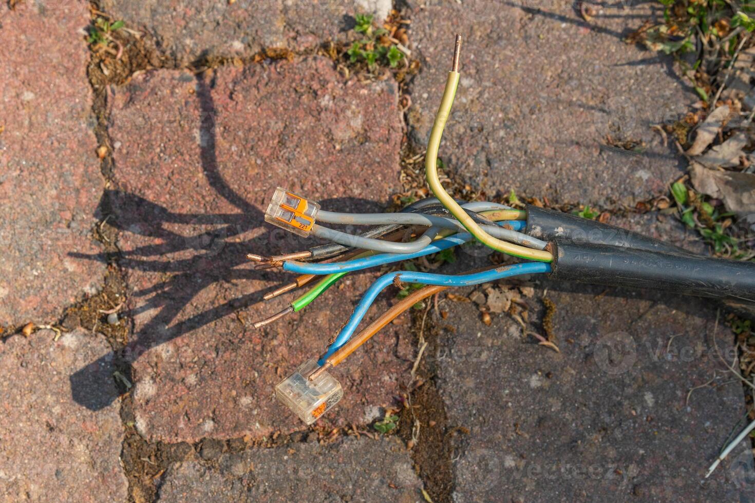 Frayed Electrical Cables on Brick Pavement Close-up photo