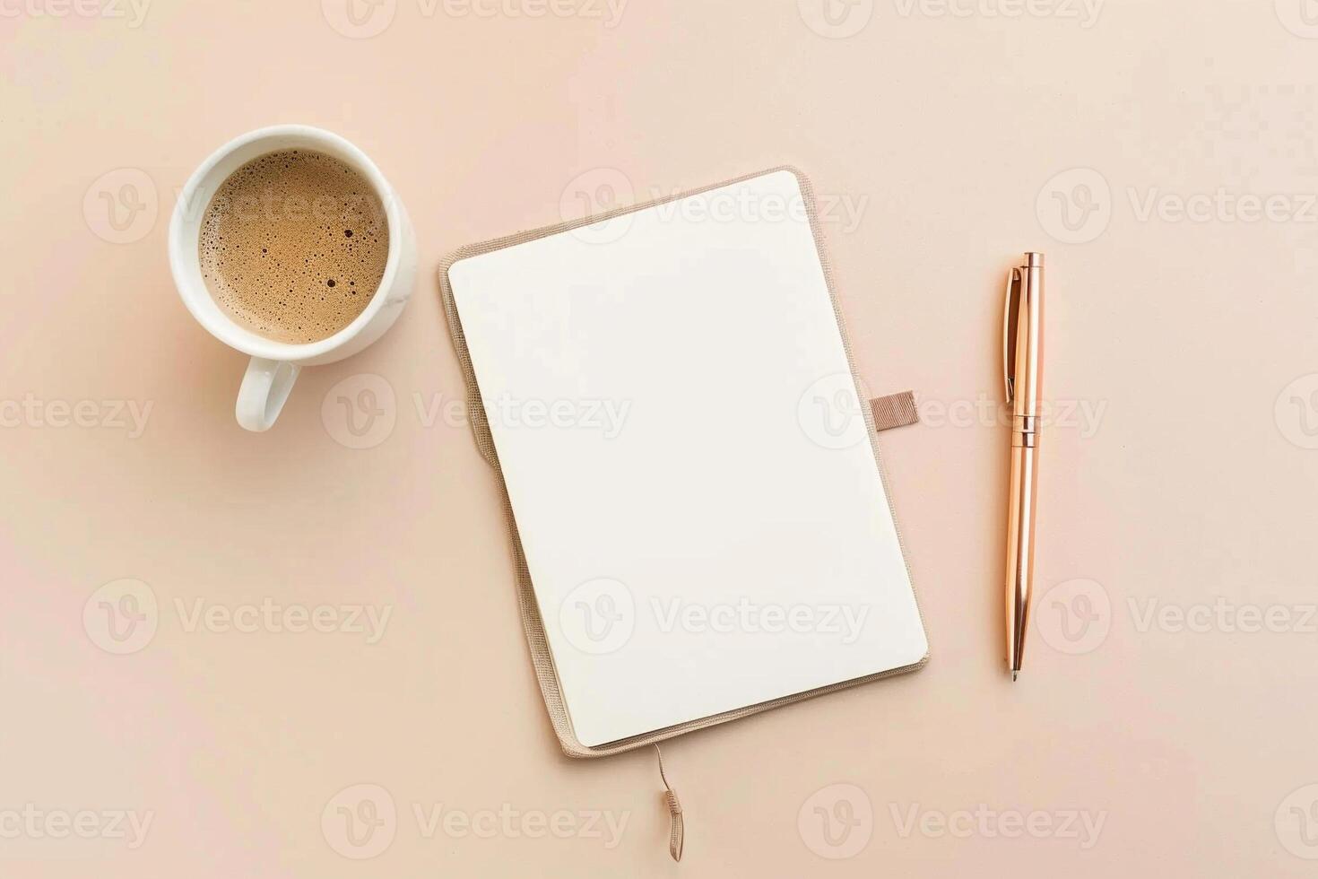 A cup of coffee sits on a table next to a pen and a blank notebook photo