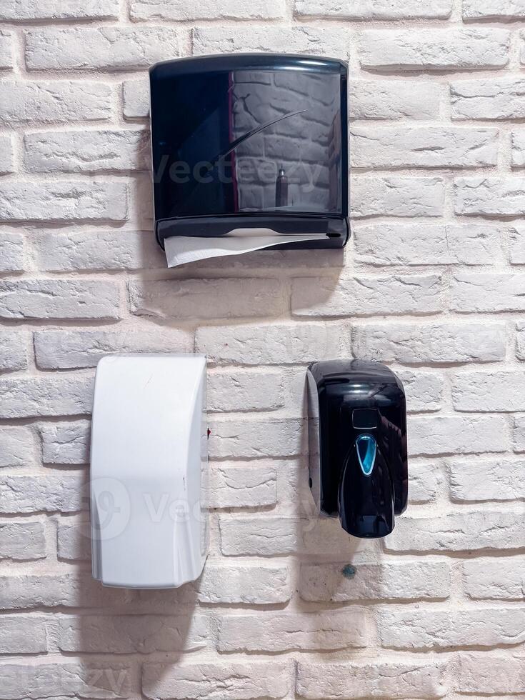Wall-mounted dispensers in a clean restroom with a modern brick design photo