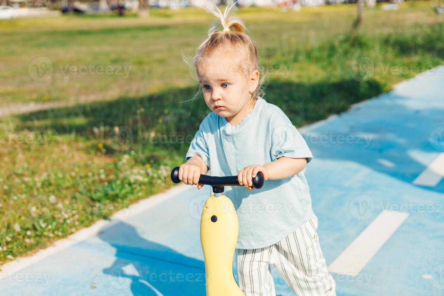 Young child riding a scooter on a sunny day in park setting photo