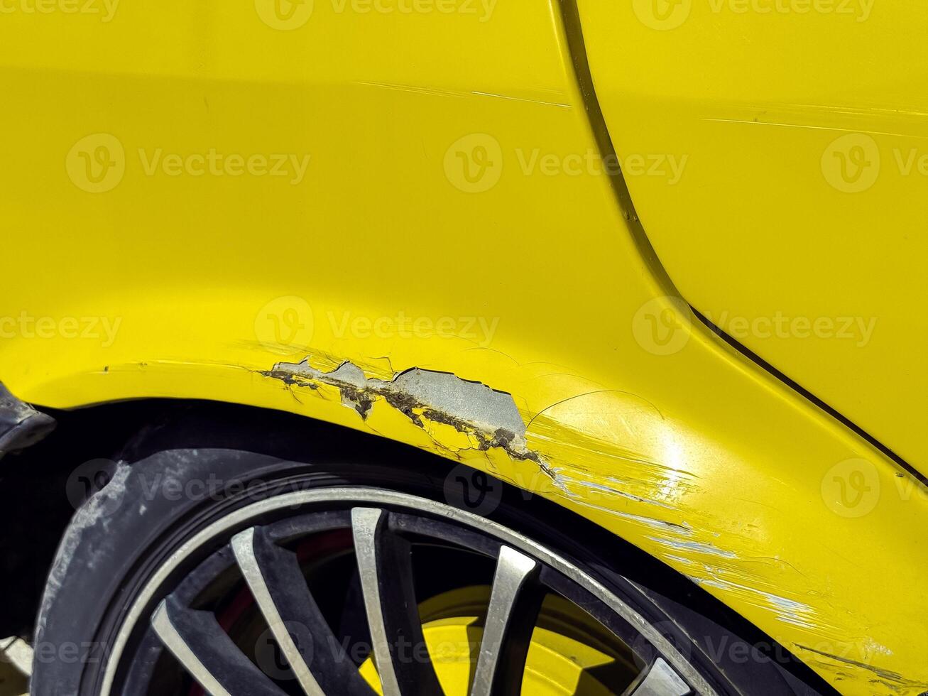 Retro Car damage on a bright yellow vehicle with scratched paint and alloy wheels in sunlight photo