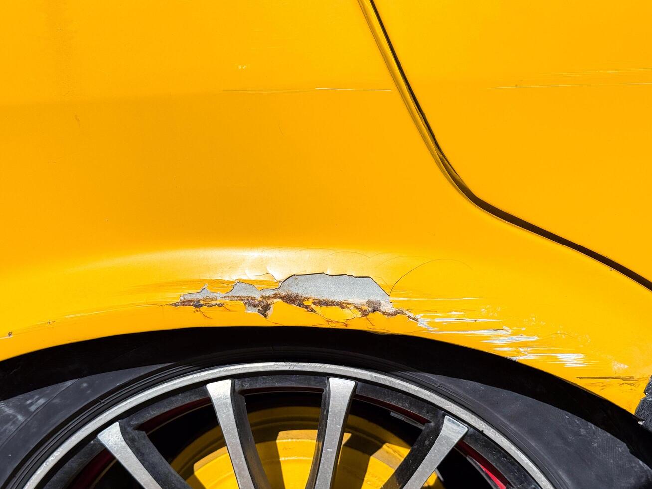 Retro Car damage on bright yellow vehicle with scratched paint and alloy wheels in sunlight photo