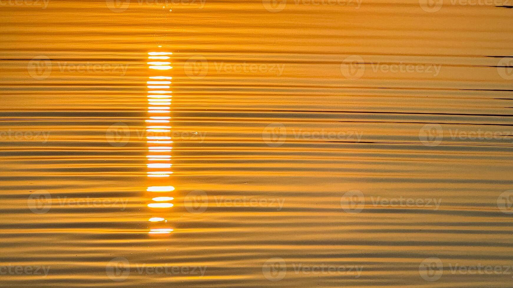 Golden sunset reflection on tranquil water with radiant ripples and soothing light captures serene evening ambiance amidst nature's beauty photo