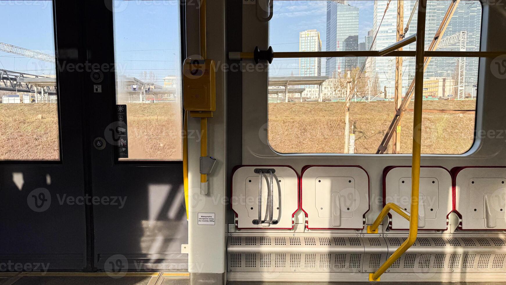 Urban train interior with sunlit windows and modern cityscape in background on a clear day highlighting urban transit and architecture photo