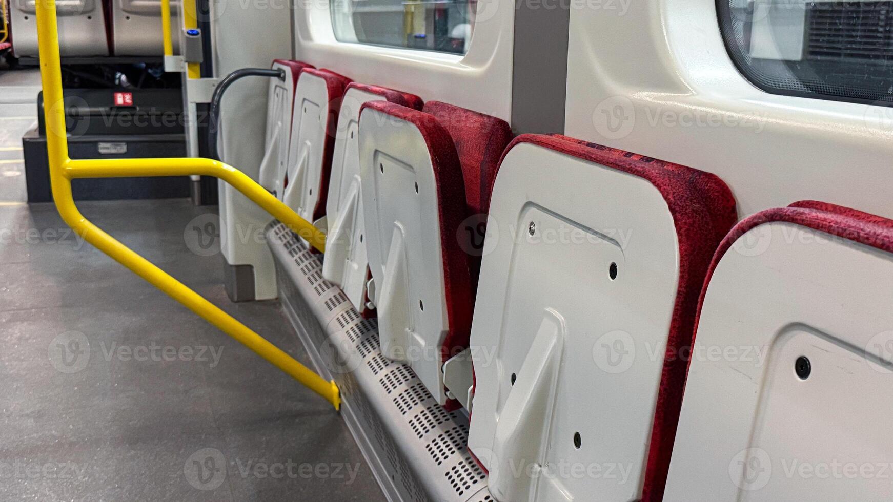 Folded red and white bus seats with yellow handrails inside an empty modern vehicle interior photo