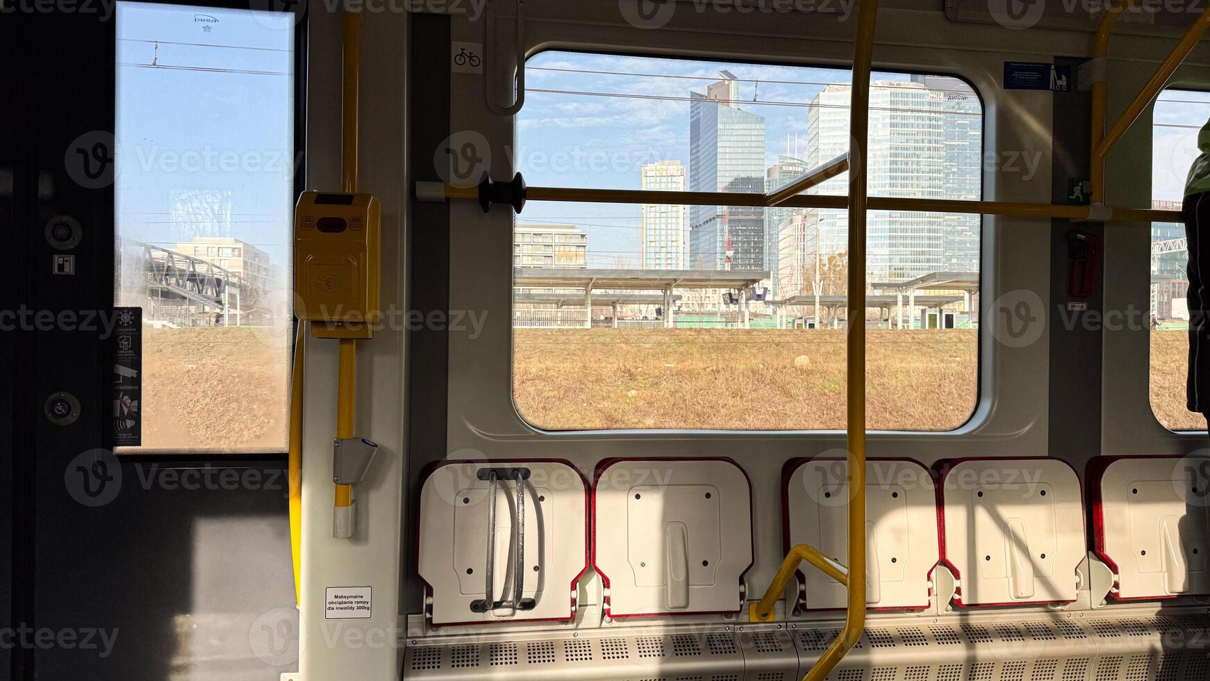 Urban train interior with empty seats and cityscape view of skyscrapers through window on a sunny day in a modern european city photo