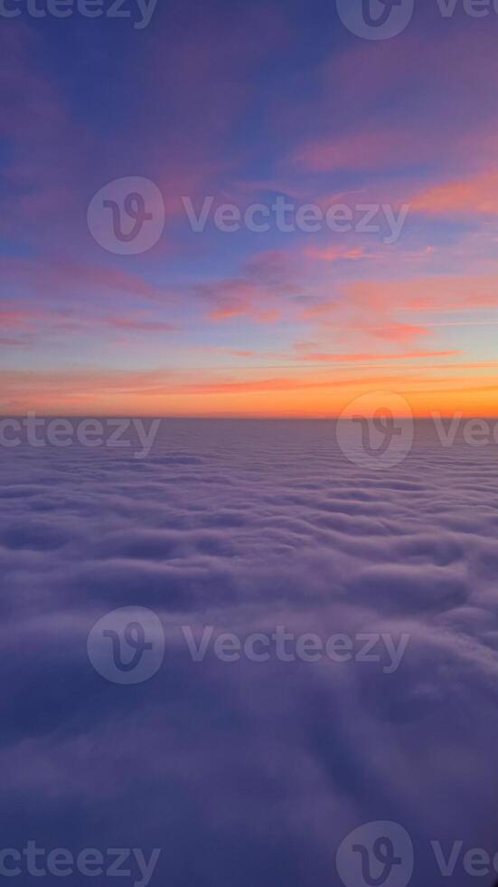 Breathtaking aerial view of purple and orange sky over fluffy clouds at sunset showcases natural beauty and serene atmosphere photo