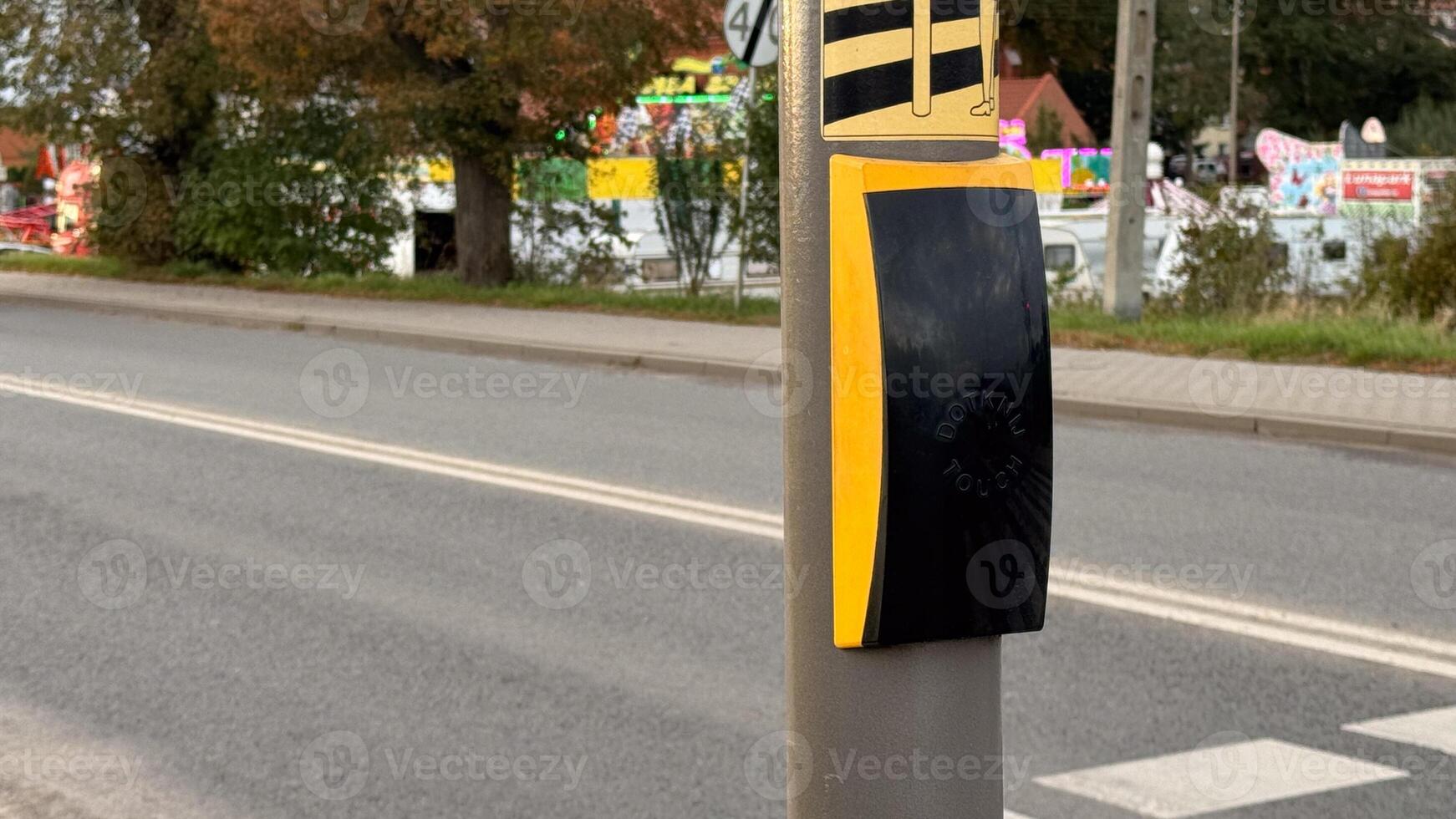 Urban crosswalk activation button with braille on busy street intersection in modern city environment featuring autumn foliage photo
