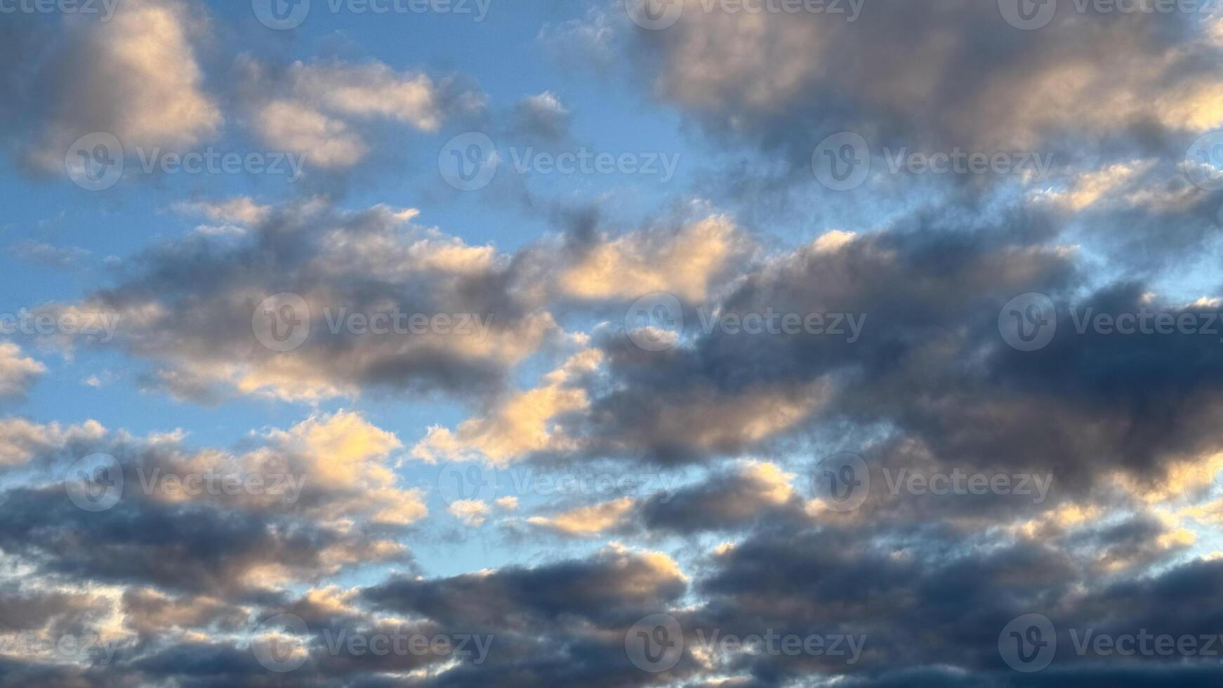 Luminous sunset clouds in a vibrant sky reflecting warmth and tranquility over a peaceful horizon of soft blue and dusky grey tones photo