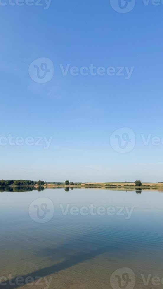 Serene landscape with tranquil lake and clear sky reflecting water surrounded by greenery horizon for peaceful outdoor experience photo