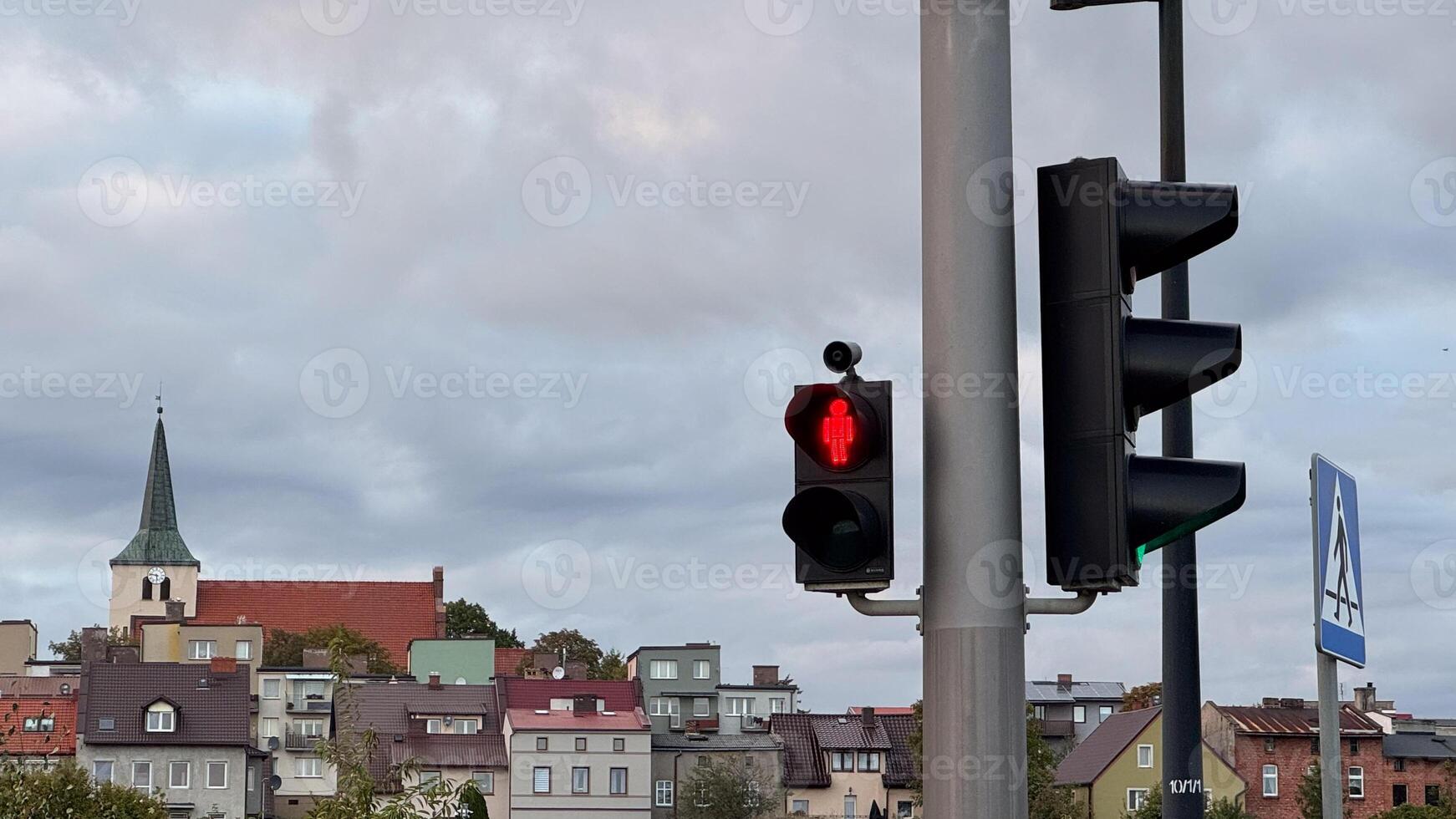Urban neighborhood with red traffic light signalized urban cityscape featuring residential roofs and overcast sky in autumn season photo
