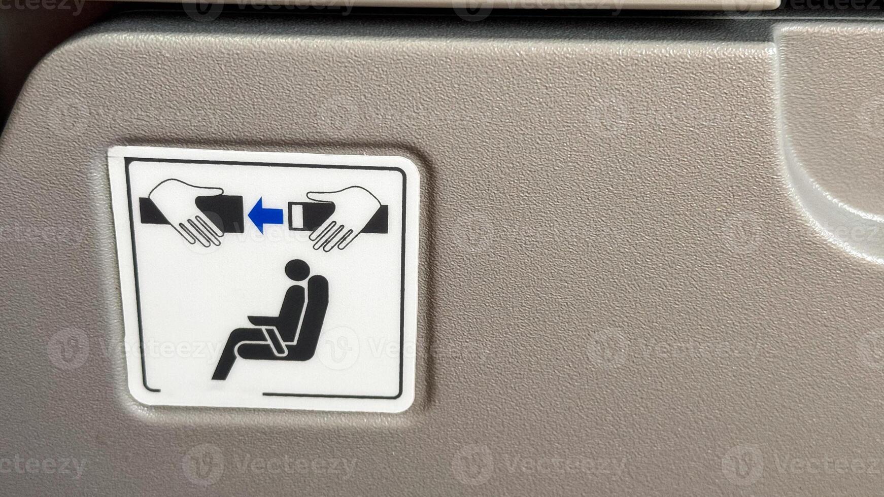 Safety sign on airplane seatback conveying the importance of seatbelt security for passengers highlighted with simple instructional graphics photo