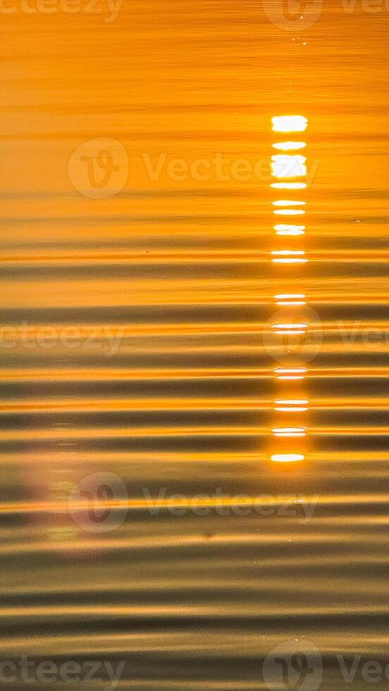 Golden sunset reflection on calm water surface with soft ripples creating a tranquil and serene ambiance capturing nature's beauty photo