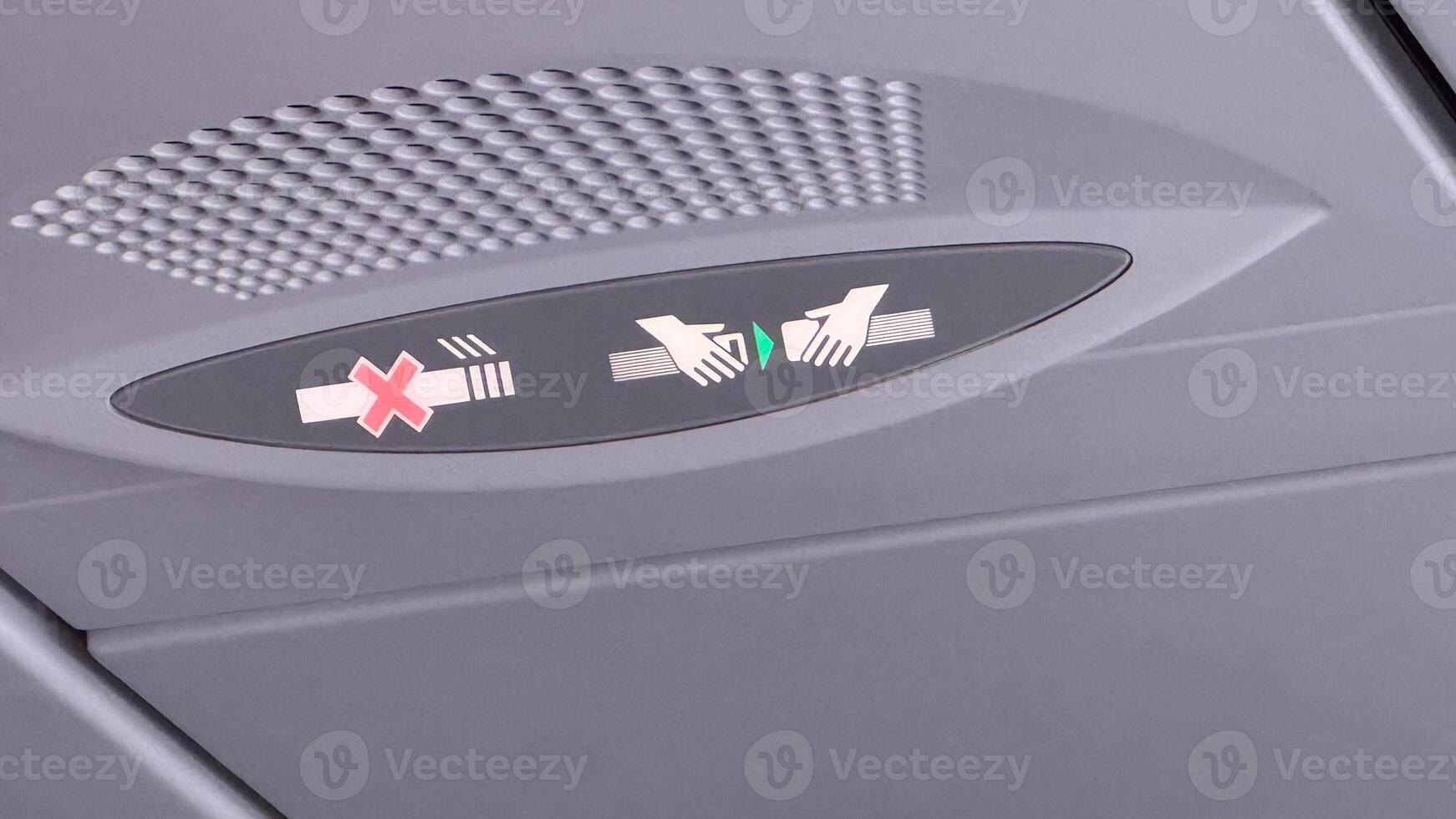 Airplane lavatory occupancy indicator with red cross and hands symbols on grey background inside commercial aircraft cabin photo