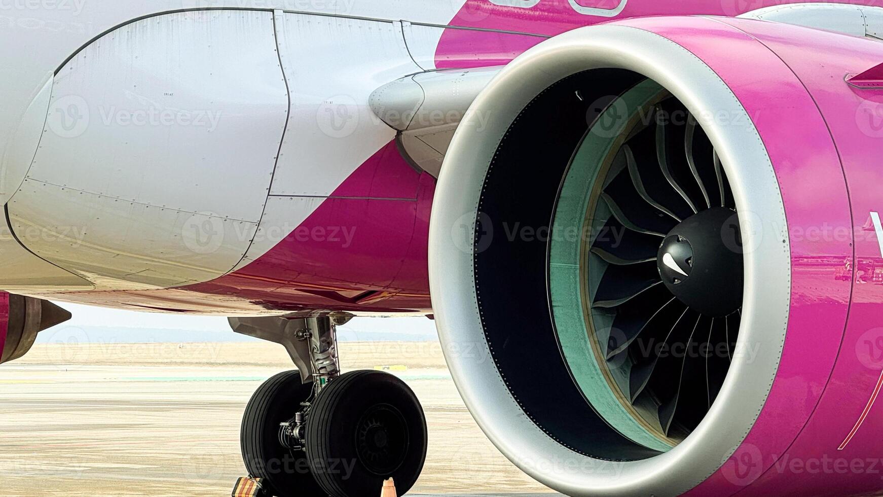 Vibrant pink and white airplane engine with wheel on runway showcasing modern aircraft design and engineering at daylight airport photo