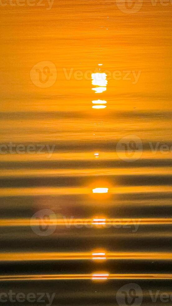 Golden sunset reflections over calm water with radiant ripples creating a serene and peaceful atmosphere amidst a warm orange glow photo
