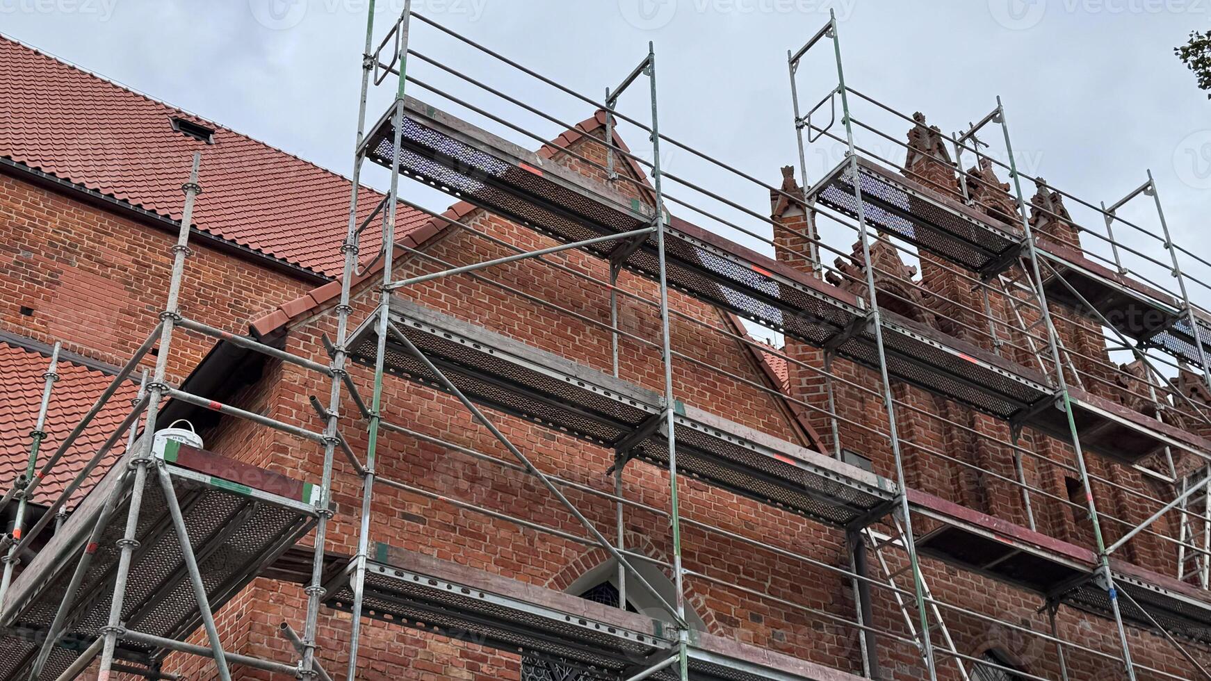 Scaffolding surrounds historic brick building under restoration on a cloudy day showcasing architectural details and renovation work photo