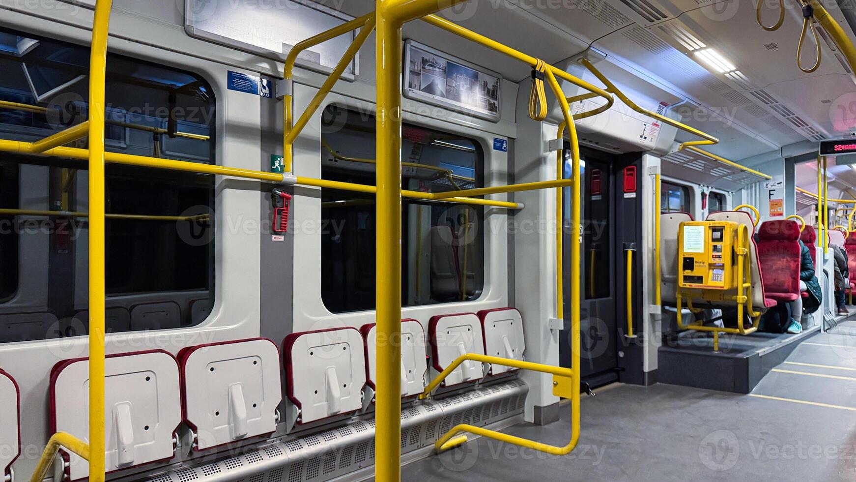 Modern city train with yellow handrails and seating arrangements for passengers in a spacious and well-lit interior creating a comfortable journey photo