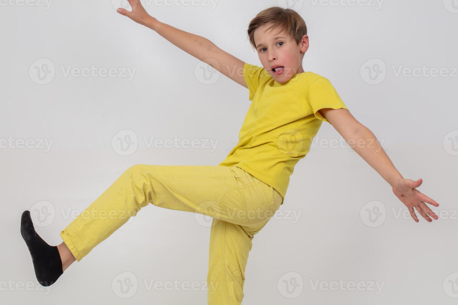 A boy in a yellow shirt and yellow pants takes a step. He is wearing black socks. Concept of playfulness and fun photo