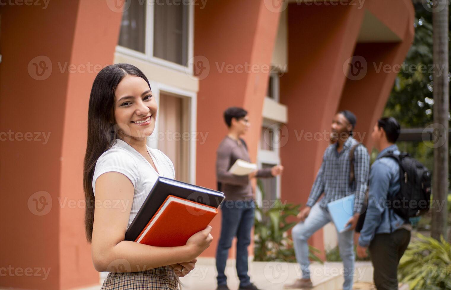 Hispanic female student smiling at university with friends in background photo