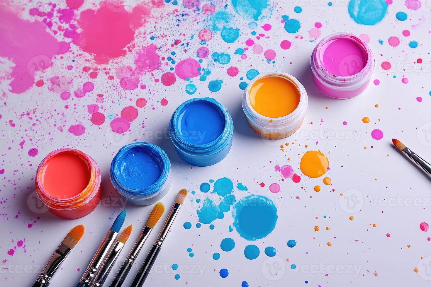 Paintbrushes and gouache jars creating colorful splashes on white background photo