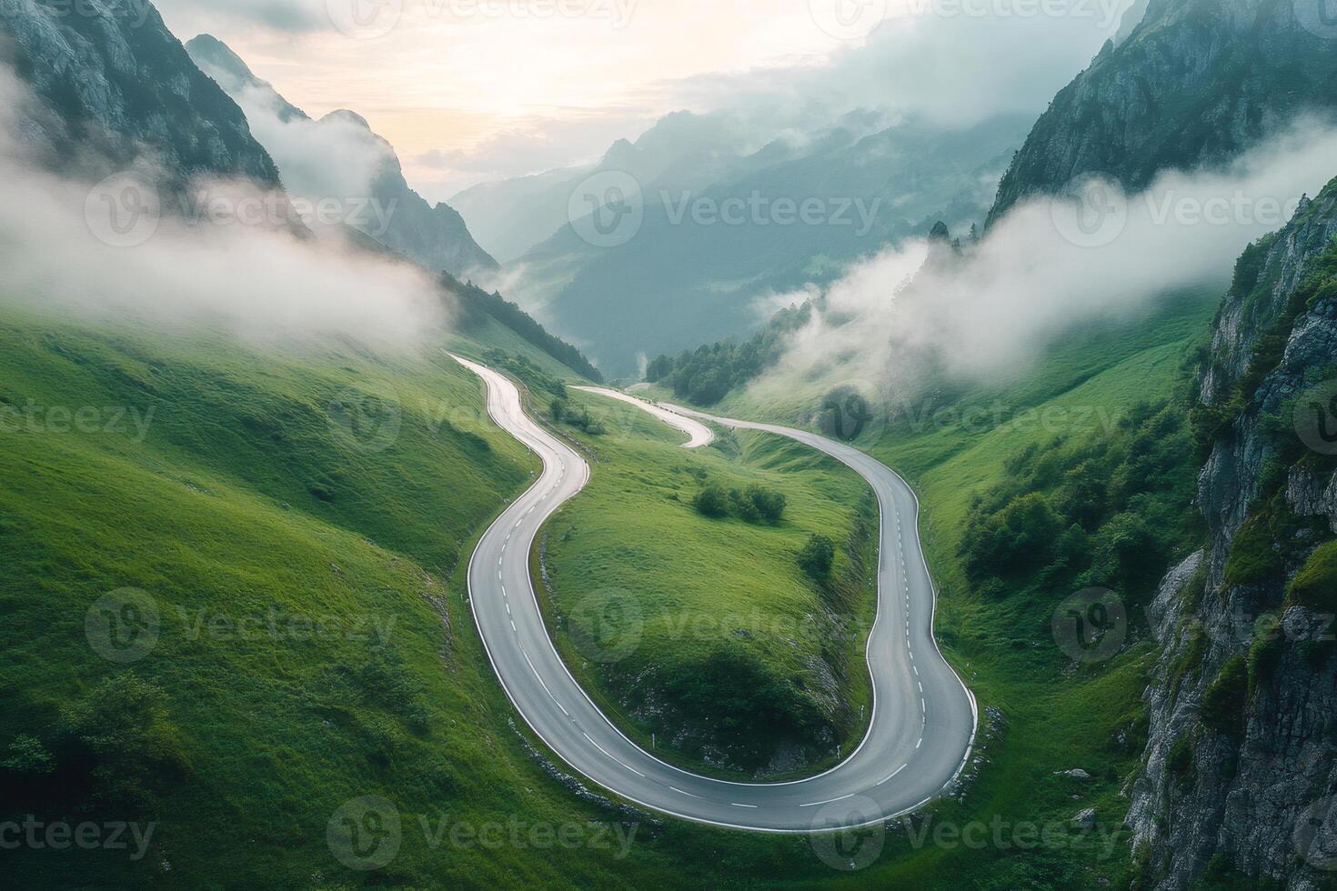 Winding road weaving through lush green mountains in the fog photo