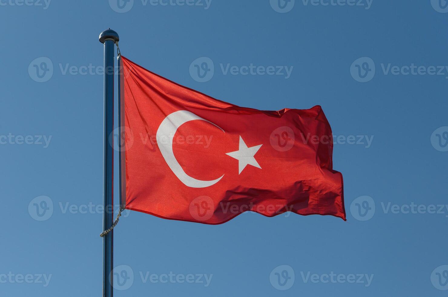 Majestic Turkish flag waving against a clear blue sky during a sunny day in Turkey photo