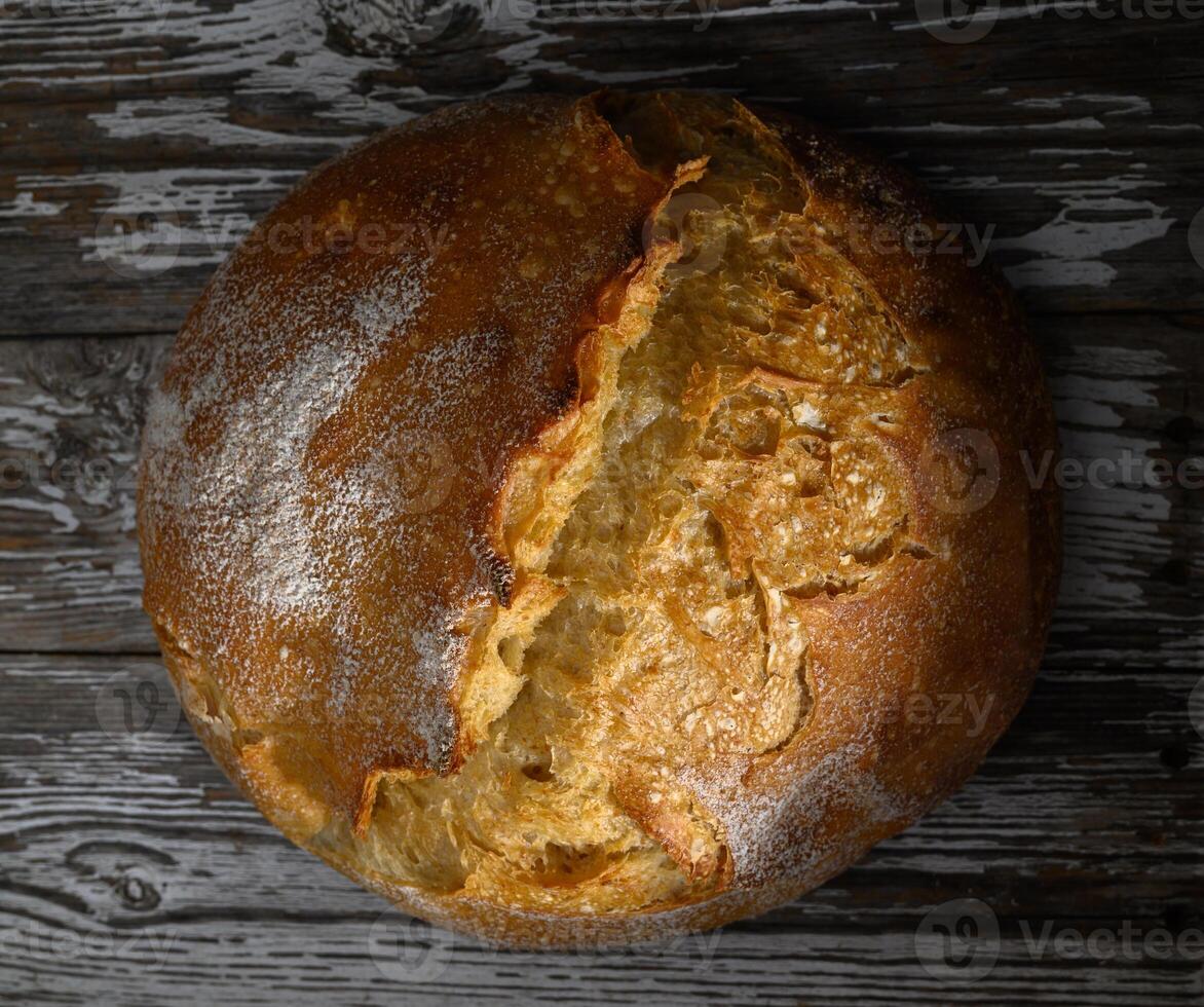 Freshly baked sourdough loaf resting on dark wooden surface with rustic charm photo