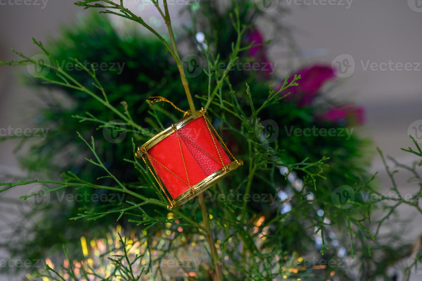 Festive red drum ornament hangs amidst lush greenery on a bright winter day 1 photo
