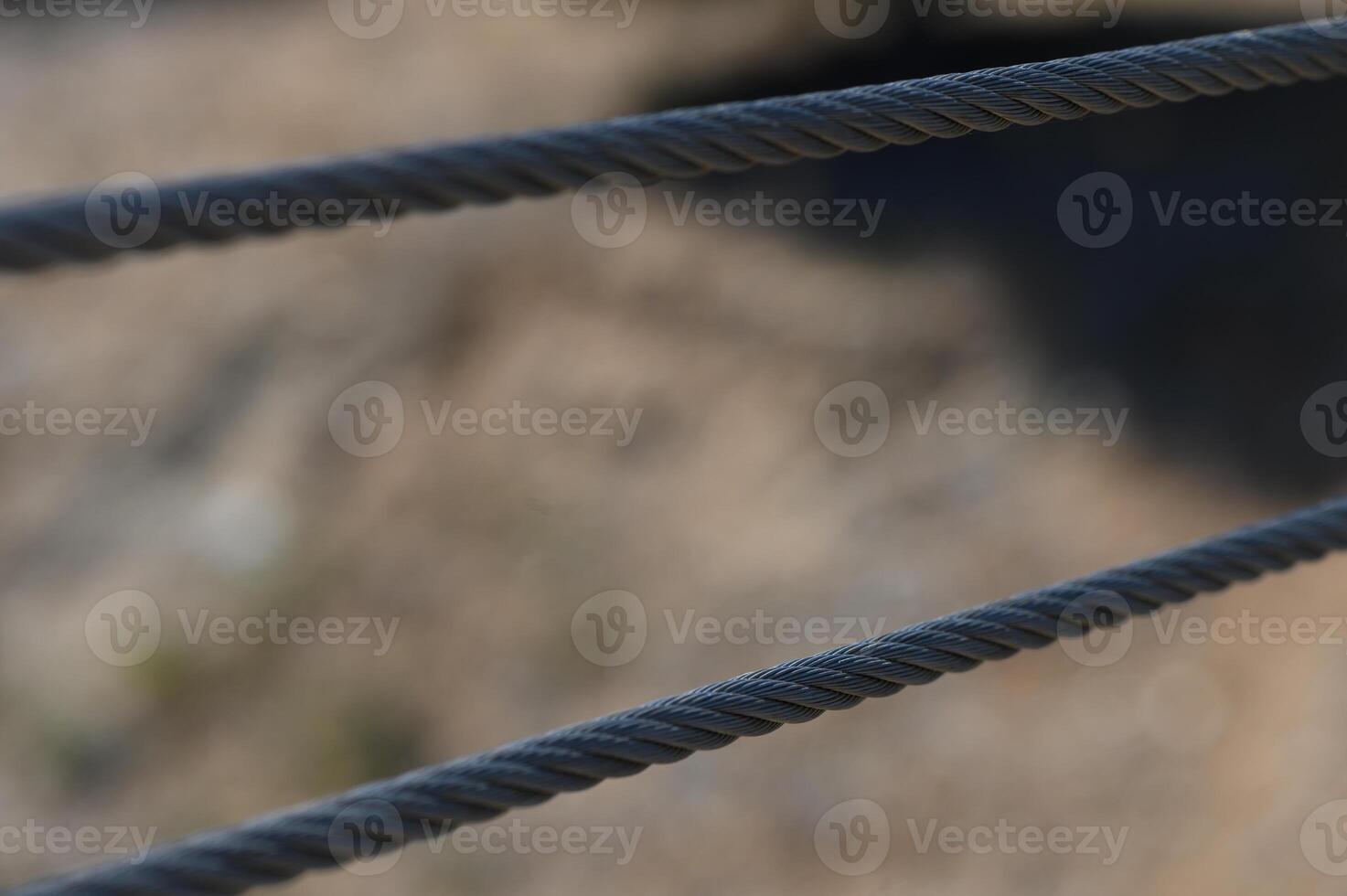Intricate patterns of twisted cables against a blurred natural backdrop reveal the beauty of everyday structures in outdoor spaces photo
