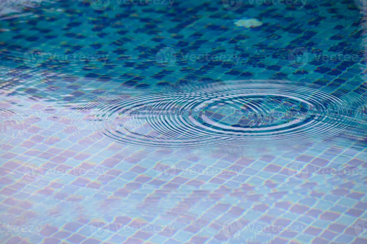Rippling patterns form on the tranquil surface of a blue-tiled pool on a sunny afternoon photo