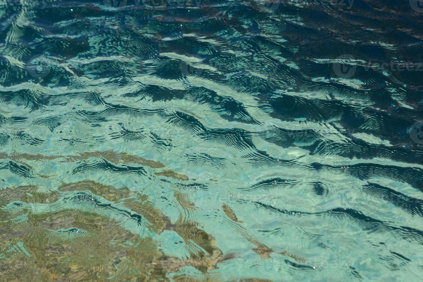 Crystal clear water rippling gently under the sun casts mesmerizing reflections on a serene summer day by the lake photo