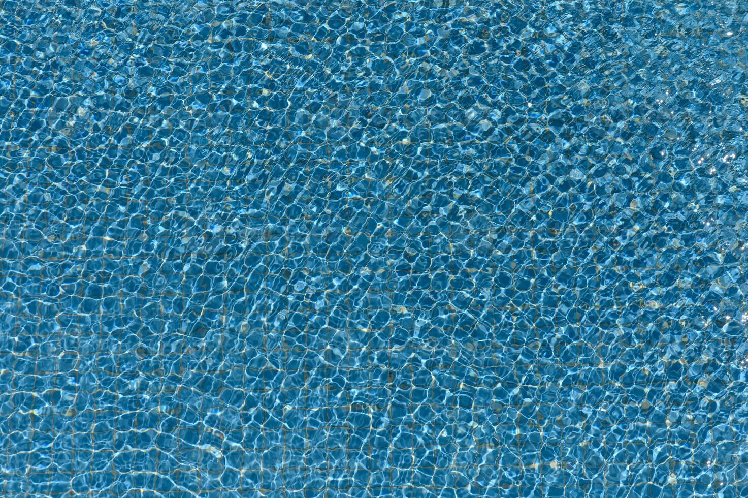 Bright sunlight playing on the surface of clear pool water, creating natural wave patterns and summer texture. photo