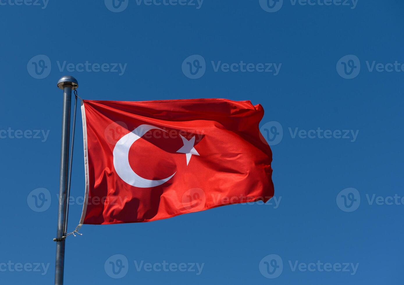 Turkish flag waving proudly against a clear blue sky during a sunny day photo