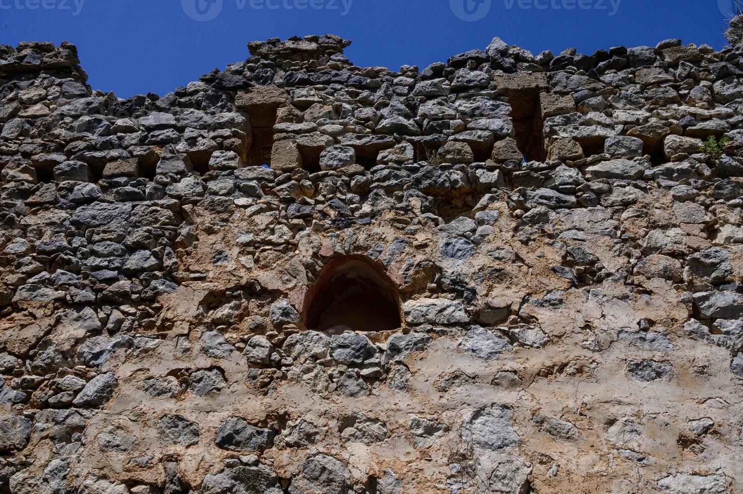 Stone-framed window inside the castle offering mountain views. Historical atmosphere and old architecture. photo
