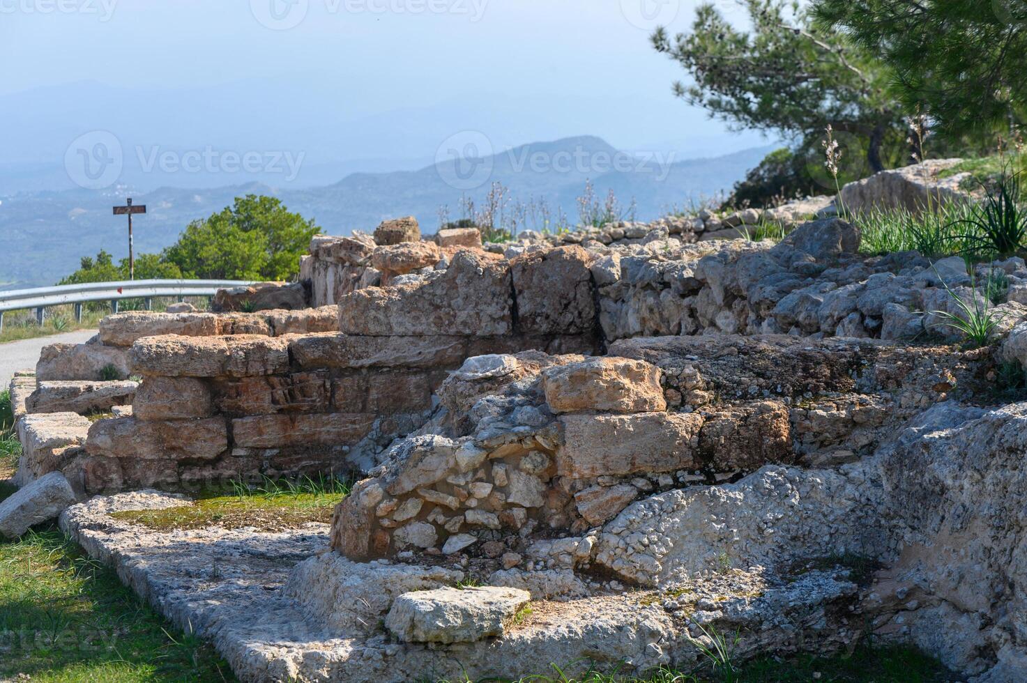 Ancient ruins overlook picturesque valley of lush greenery and distant mountains photo