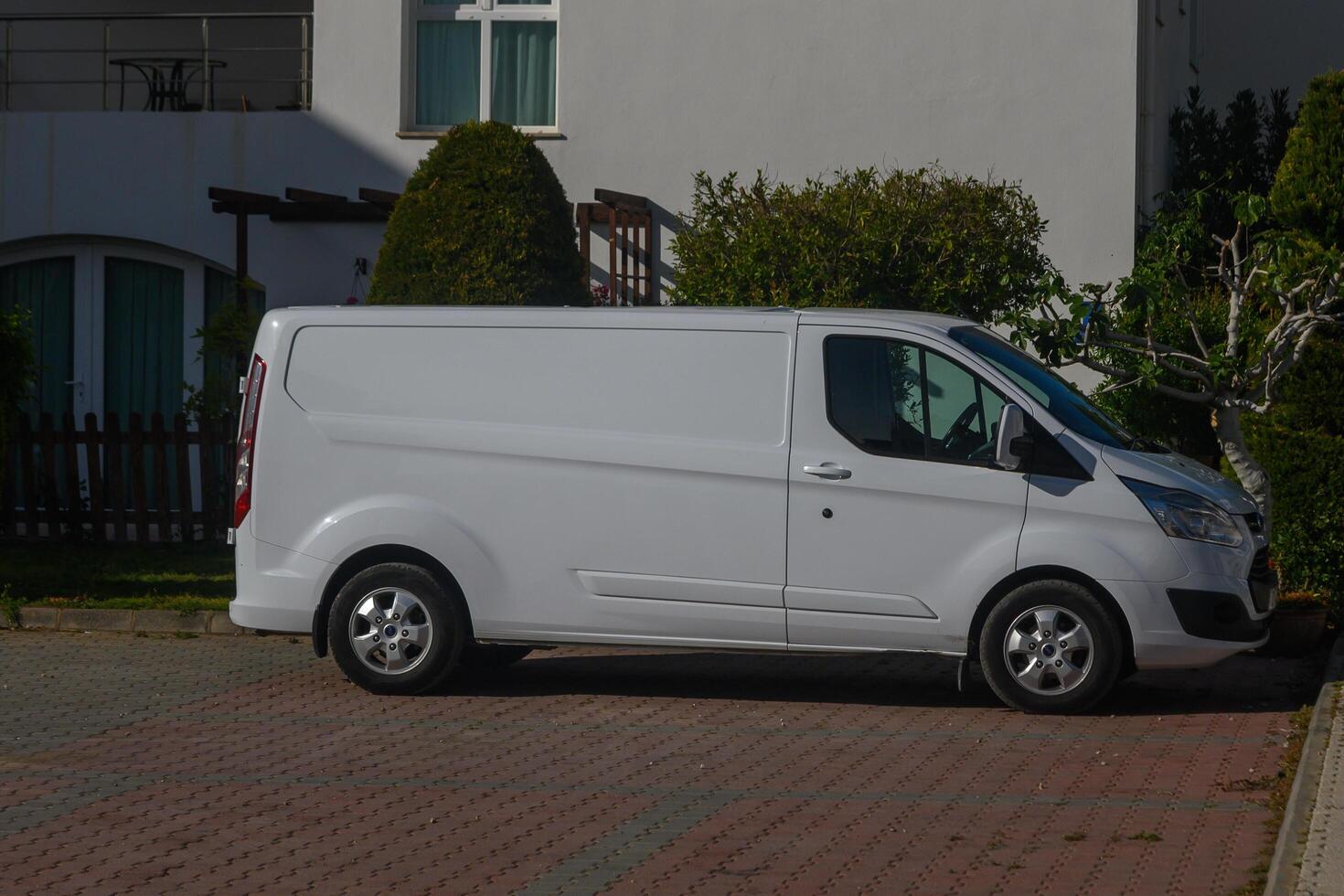 Gaziveren Cyprus -16.04.2025 Parked white delivery van standing on a quiet residential street in the morning light, surrounded by greenery and a peaceful atmosphere photo