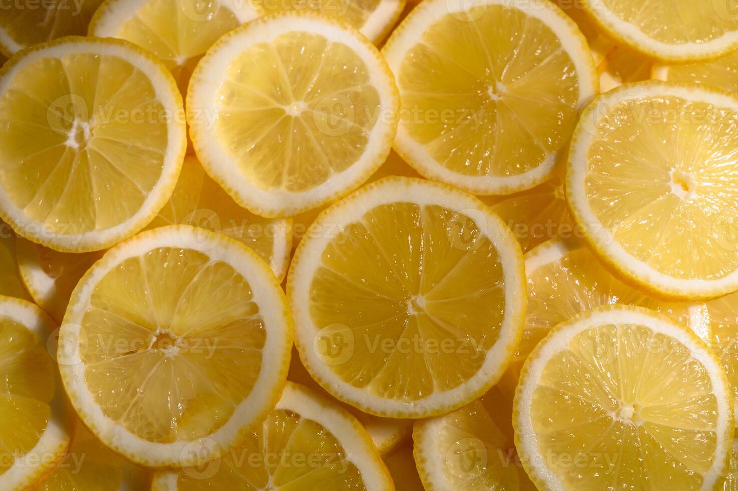 Bright yellow lemon slices layered beautifully on a textured surface showcasing photo