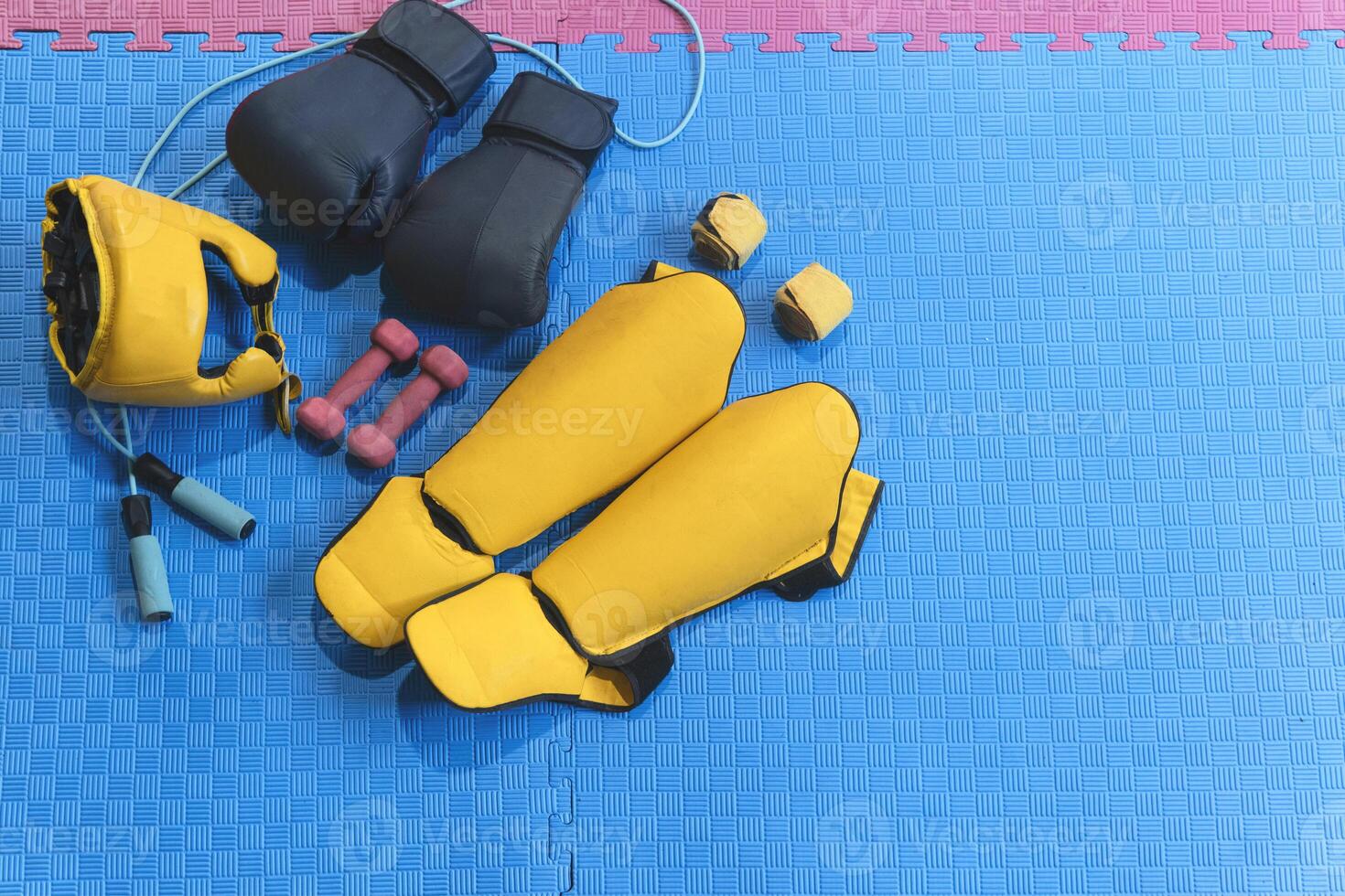 Boxing equipment lying on blue mat with pink edge ready for training photo