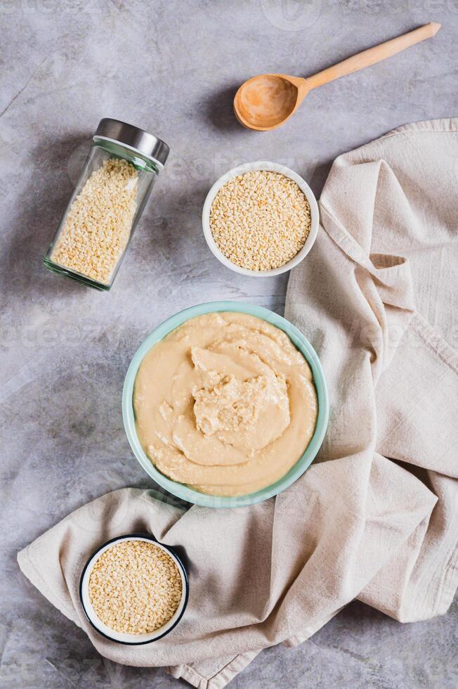 Homemade sesame tahini in bowl on grey table top and vertical view photo