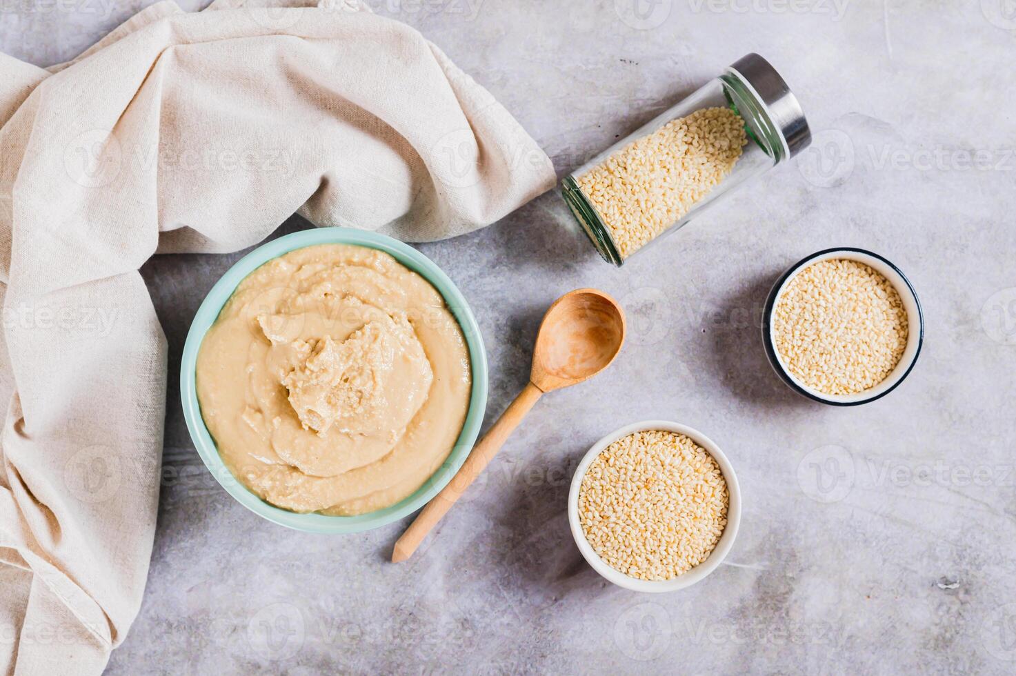 Sesame tahini in a bowl and sesame seeds in a bowl on the table top view photo